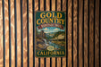 A vintage-style metal sign for the Gold Country Heritage Trail in California, featuring an illustration of a waterfall and a panning gold mine.