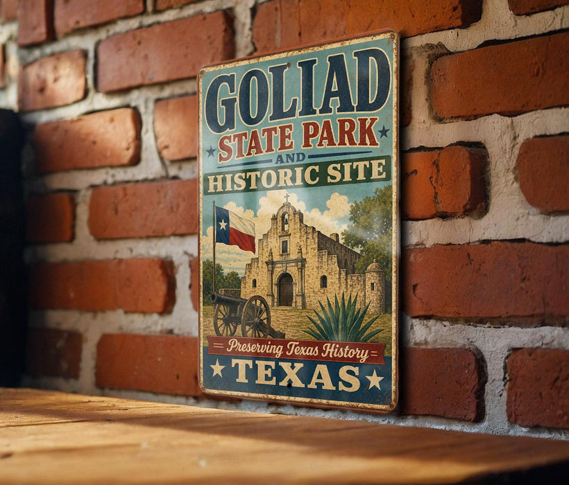 A vintage-style sign for Goliad State Park and Historic Site, featuring an illustration of a historic building and a wagon wheel.