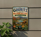 A vintage metal sign advertising the Gouritz Cluster Biosphere Reserve in South Africa, featuring a scenic landscape with mountains, rivers, and wildlife.