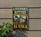 A vintage-style metal sign for Governor's mansion in Alaska, featuring a large image of the mansion and the state's flag.