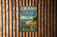 A vintage metal sign for Grand Beach Provincial Park in Manitoba, Canada, featuring a scenic beach landscape with a wooden fence in the background.