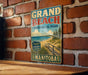 A vintage-style metal sign for Grand Beach Provincial Park in Manitoba, Canada, featuring a scenic beach landscape with a wooden walkway leading to the beach.