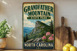 A vintage-style sign for Grandfather Mountain State Park in North Carolina, featuring a mountain landscape with pine trees and pink flowers.
