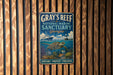 A vintage metal sign for the Gray's Reef National Marine Sanctuary in Georgia, featuring an illustration of a turtle swimming among coral and fish.