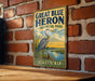 A vintage-style sign for Great Blue Heron Provincial Park in Saskatchewan, featuring a heron standing on a log near a river.