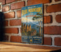 A vintage-style metal sign with the text "GREATER BLUE MOUNTAINS AREA AUSTRALIA" and "SPECTRacular Scenery - World Heritage Explore Discover Experience Nature's Masterpiece" is displayed on a brick wall.