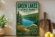 A vintage-style metal sign for Green Lakes State Park in New York, featuring a scenic image of the lake surrounded by trees and mountains.