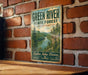 A vintage-style metal sign for the Green River State Forest in Kentucky, featuring a scenic image of the river surrounded by lush forests.