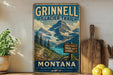 A vintage-style metal sign for the Grinnell Glacier Trail in Montana, featuring a scenic mountain landscape with a trail and signs indicating the trail's name and direction.