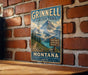 A vintage-style metal sign for the Grinnell Glacier Trail in Montana, featuring a mountain landscape and trail signs.