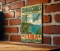 A vintage-style sign for the Guianacabibles Biosphere Reserve in Cuba, featuring a tropical landscape with palm trees, a bird, and a body of water.