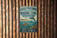 A metal sign with text and illustrations of marine life, including a dolphin and turtle, is displayed on a wooden wall.