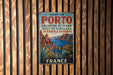 A vintage metal sign for the Gulf of Porto, Portugal, featuring a scenic landscape with mountains, a bay, and palm trees.