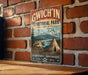 A vintage-style sign for GWICH'IN TERRITORIAL PARK, featuring a mountain landscape and a teepee, mounted on a brick wall.