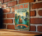 A vintage-style metal sign for Halong Bay, Vietnam, featuring a scenic illustration of the bay with palm trees and boats.