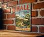 A vintage metal sign for Hale Farm and Village, featuring an illustration of a farm scene with a horse-drawn carriage, mounted on a brick wall.