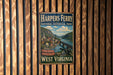 A vintage-style metal sign for Harpers Ferry National Historical Park, featuring a scenic image of the park and its surroundings.