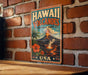 A vintage-style metal sign with the text "HAWAII VOLCANOES NATIONAL PARK USA" displayed on a brick wall.