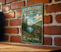 A vintage-style metal sign for Hemlock-Canadice State Forest in New York, featuring a scenic landscape with a lake and mountains.