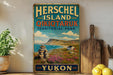 A vintage-style sign for Herschel Island, Qikiqtaruk, and Territorial Park, with a scenic landscape of mountains, a river, and a small village.