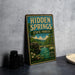 a vintage-style sign for Hidden Springs State Forest in Illinois, with a scenic illustration of a forest and a river.