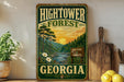 A vintage-style sign for the Hightower Forest in Georgia, featuring a scenic landscape with pine trees, a river, and a sunset.