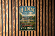 A vintage-style sign for Hildene, the Lincoln Family Home, mounted on a wooden wall.