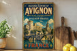 a vintage-style sign for the Historic Centre of Avignon, France, with a castle and bridge depicted on it. The sign is displayed on a shelf next to a wooden cutting board and some potted plants.