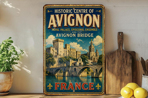 a vintage-style sign for the Historic Centre of Avignon, France, with a castle and bridge depicted on it. The sign is displayed on a shelf next to a wooden cutting board and some potted plants.