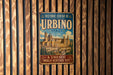 A vintage metal sign for the Historic Centre of Urbino, Italy, featuring an illustration of the historic city of Urbino.