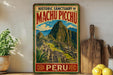 A vintage-style metal sign displaying the historic sanctuary of Machu Picchu, with a mountainous landscape and Inca ruins in the background.