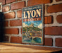 A vintage-style metal sign displaying the text "HISTORIC SITE OF LYON FRANCE" with an illustration of a cityscape and a river.
