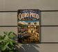 A vintage-style metal sign for the historic town of Ouro Preto, Brazil, featuring an illustration of a historic church and buildings.