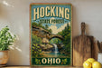 A vintage-style metal sign for Hocking State Forest in Ohio, featuring a scenic landscape with a waterfall and trees.