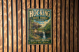 A vintage-style metal sign for Hocking State Forest in Ohio, featuring a scenic image of a waterfall and forest.