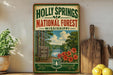 A vintage-style sign for the Holly Springs National Forest in Mississippi, featuring a scenic illustration of a forest and a river.