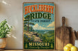 A vintage-style sign for Huckleberry Ridge State Forest in Missouri, featuring a scenic mountain landscape with pine trees and a river.