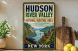 A vintage-style sign for the Hudson River Valley National Heritage Area in New York, featuring a scenic illustration of a river, mountains, and a train.