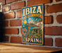 A vintage-style metal sign with the text "IBIZA Biodiversity & Culture" and "SPAIN" is displayed on a brick wall.