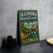 A vintage metal sign for the Illinois and Michigan Canal, featuring an illustration of a horse-drawn carriage and a building, is displayed on a gray countertop.