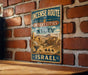 A vintage-style metal sign with the text "INCENSE ROUTE DESERT CITIES IN THE NEGEV ISRAEL" is displayed on a brick wall.