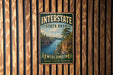 A vintage metal sign for Interstate State Park in Wisconsin, featuring a scenic landscape with a river and mountains.