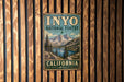 A vintage-style metal sign for Inyo National Forest in California, featuring a scenic mountain landscape.