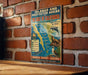 A vintage metal sign on a brick wall, featuring a map of the Gulf of California and various wildlife illustrations, including a dolphin, a seal, and a sea turtle.