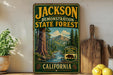 A vintage-style sign for the Jackson State Forest in California, featuring a scenic illustration of a forest with a river and mountains.