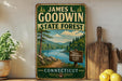 A vintage-style sign for James L. Goodwin State Forest in Connecticut, featuring a scenic landscape with a lake, mountains, and pine trees.