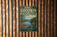 A vintage metal sign for James L. Goodwin State Forest in Connecticut, featuring a scenic landscape with a lake, mountains, and pine trees.