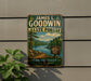 A vintage metal sign for James L. Goodwin State Forest in Connecticut, featuring a scenic landscape with a lake, mountains, and pine trees.