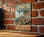 A vintage-style sign advertising the Joggins Fossil Cliffs, a world heritage site in Canada, is displayed on a brick wall.