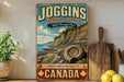 A vintage-style sign advertising the Joggins Fossil Cliffs in Canada, featuring a scenic image of the cliffs and a fossilized shell.